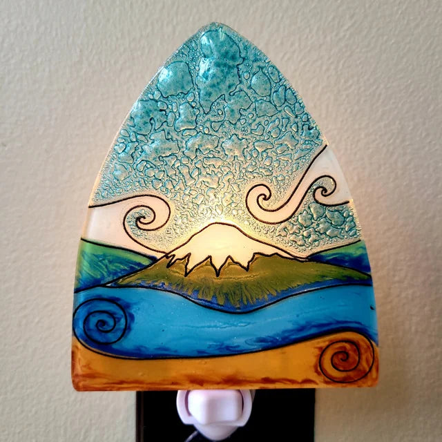 A photo of a nightlight made of recycled glass in Ecuador. This night light features a mountain view landscape