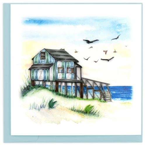 A photo of a greeting card made of quilling art from Vietnam. This card features a beach house scene with water in the background and birds in the sky on the front.
