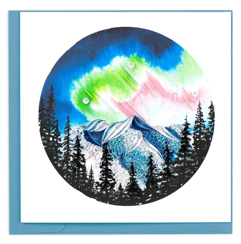 A photo of a greeting card made of quilling art from Vietnam. This card features a northern lights scene on the front, with a mountain and trees while the colorful sky is above on the front.