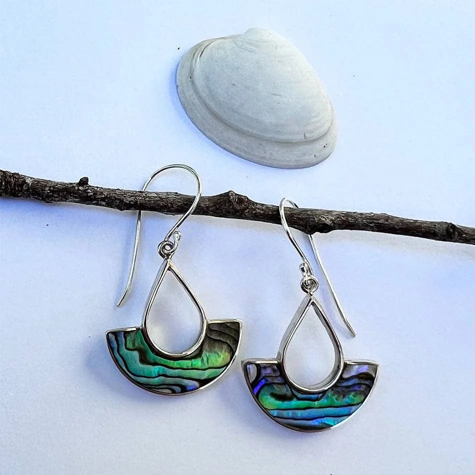 A photo of a pair of earrings that are teardrop shape sterling silver with a half moon on the bottom of the teardrop that is made with abalone shell from Bali, Indonesia. 