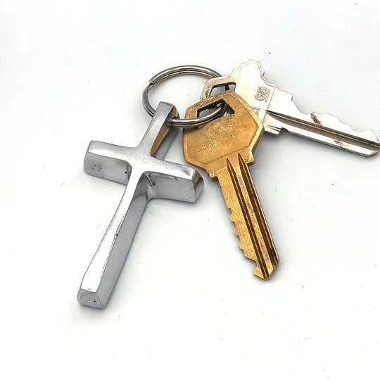A photo of a keychain made from recycled car parts in Nicaragua. This keychain is in the shape of a Cross. 