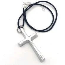 A photo of a necklace with a silk cord and a pendant made from recycled car parts in Nicaragua. This pendant is in the shape of a cross. 