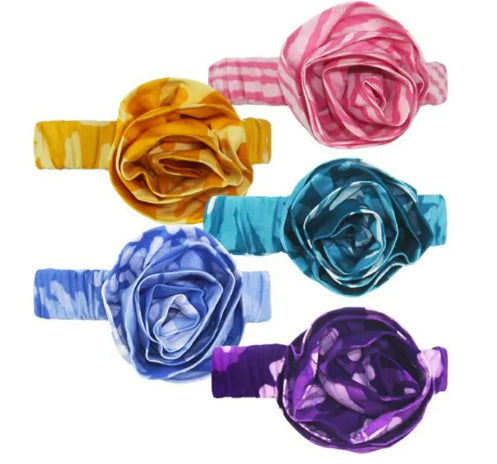 A photo of an assortment of baby headbands with a rosette on them. Colors vary from purple, light blue, green, yellow, and pink. 