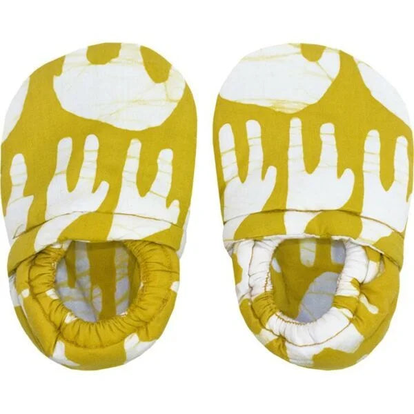 A photo of a pair of crawling shoes for babies. Made fair trade in ghana, these shoes feature a yellow shoe with white animals like a giraffes and elephants.