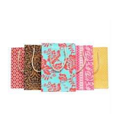 A photo of gift bags. This is the medium size that are made of cotton recycled material. The photo shows a variety of colors and designs. 