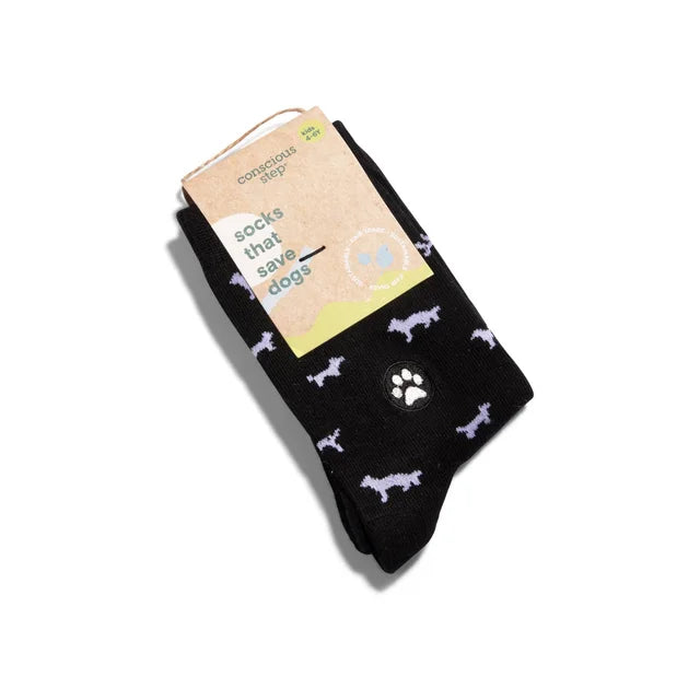 A photo of a pair of black kids socks with white dog outlines on them and the packaging that reads "Socks that Save Dogs".