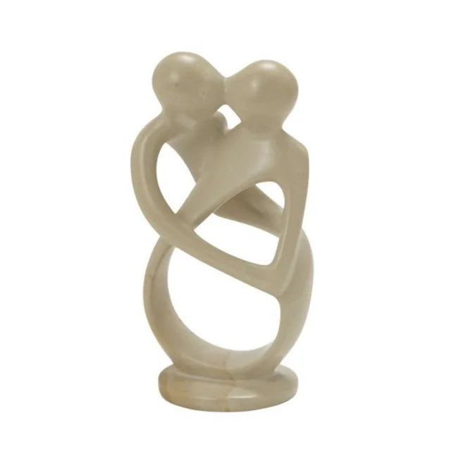 A photo of the 'eternal love' soapstone sculpture from Kenya. It is a handcarved and handsanded decor piece with white, grey, and a natural pink texture in the shape of 2 people kissing and dancing or hugging. 
