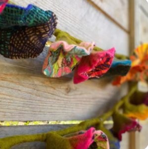 A photo of garland that has colorful felt flowers with designs on them all made of felt from Nepal. 