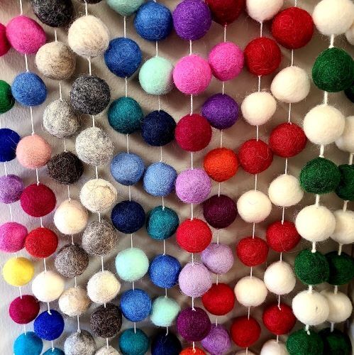A photo of felt garland made in nepal. This one is a colorful balls of felt. Their is an assortment of garland colors including; multicolor, natural grays, blues, sunrise variety, red & white, and green & white.