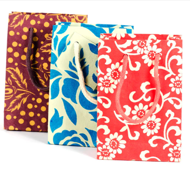 A photo of an assortment of gift bags. This one shows a variety of 3 bags ranging in color and design with red with flowers, blue with leaves design, or purple with yellow polka dots and florals. 