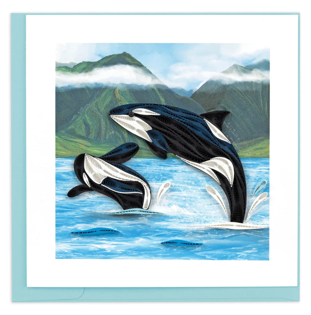 Two orcas jumping out of the water with a mountainous background