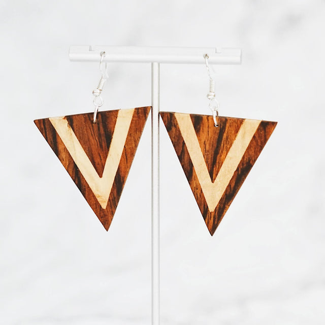 A photo of a pair of earrings that are triangle's pointing down with reclaimed wood of different colors.