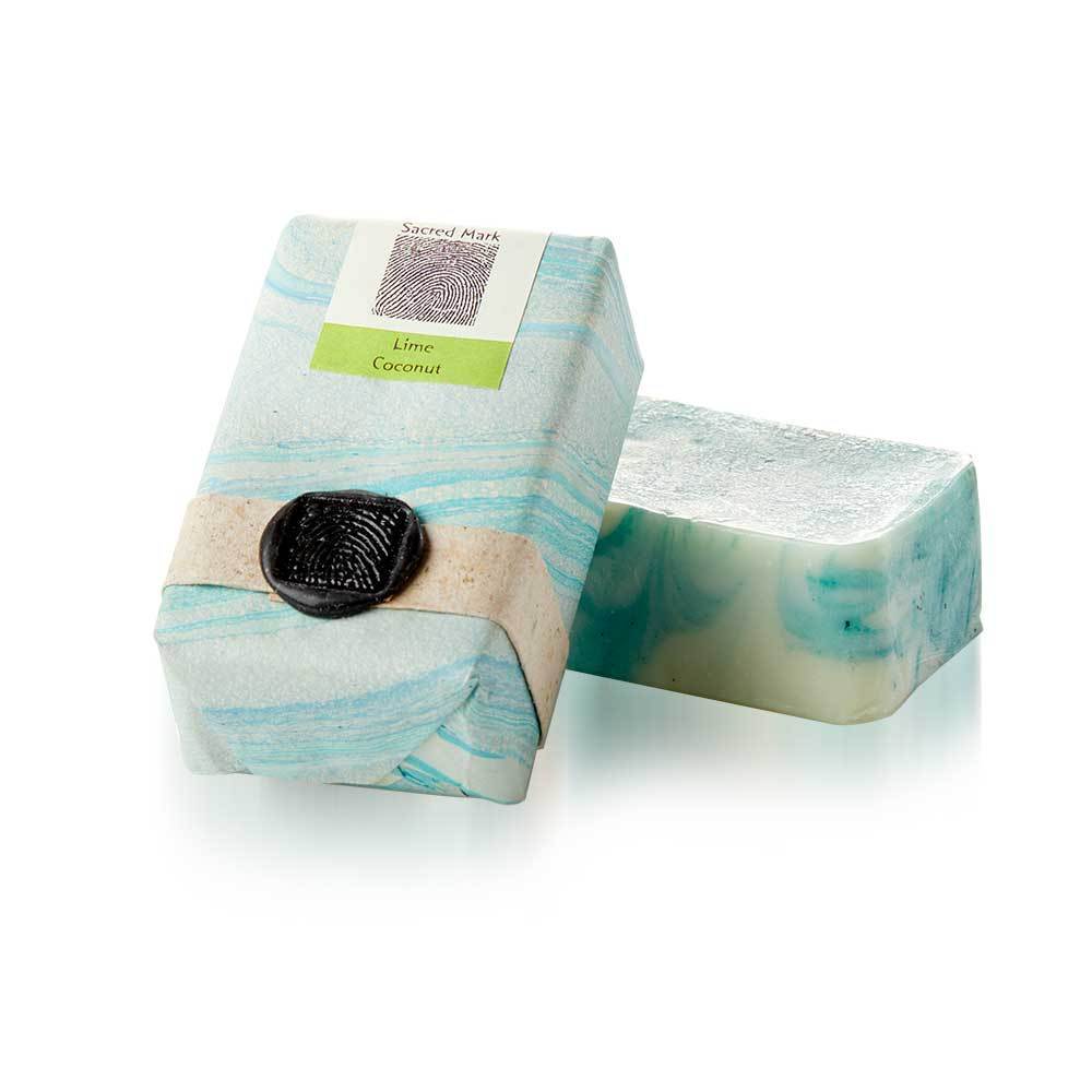 A photo of a Lime Coconut marbled soap bar, with a packaged soap bar angled sitting on top. Made bySacred Mark in Bangladesh in a wrapping made of Lokta fair trade paper.