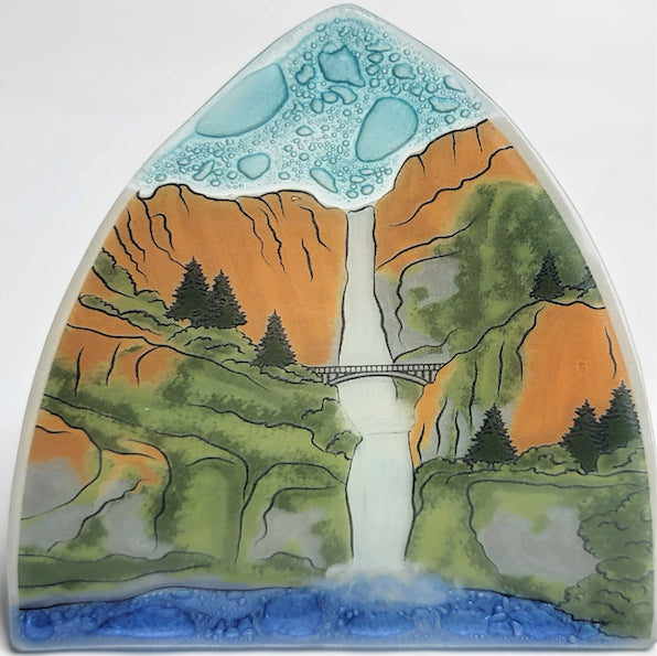 A photo of a nightlight made of recycled glass in Ecuador. This night light features Multnomah Falls, a famous waterfall with bridge scene located in Oregon. 