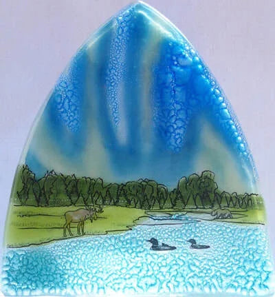 A photo of a nightlight made of recycled glass in Ecuador. This night light features a gorgeous nature scene with a moose and a pair of loons in the water with Northern Lights above. 