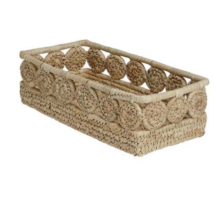 A photo of a natural grass basket with palm medallions decorated around the rectangle basket. 