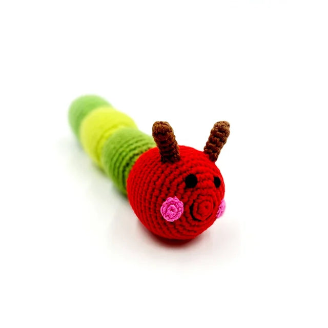 A photo of a hand crocheted rattle made in Bangladesh. This one is a caterpillar with a green body and red head, a play off of the book "The Very Hungry Caterpillar".