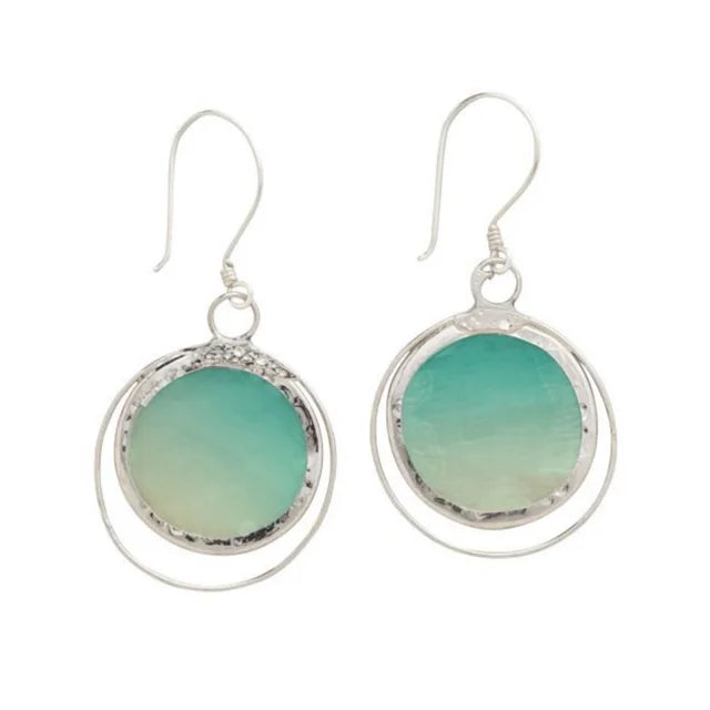 A photo of a pair of earrings made from capiz shells from the Philippines. This one shows the shells in green ombre circles giving sea horizon vibes with silver design work and hooks.