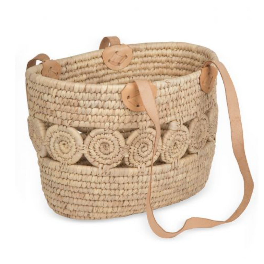 A photo of a basket tote from Bangladesh. It has woven medallions to enhance this well-crafted palm leaf basket. Strong sewn leather straps make a sturdy basket that will last.