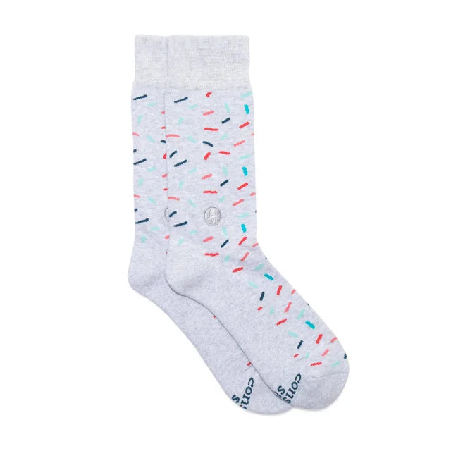 A photo of a pair of socks that give back to non-profits. These ones are grey long socks with colorful confetti on them that help find a cure. 