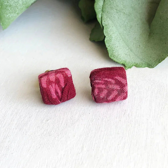 A photo of a pair of earrings that are square studs that are covered in sari material from India. 