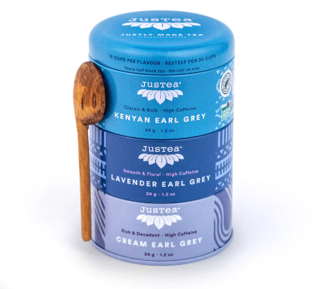 A photo of a tea trio from Justea. The tea comes in a 3 pack canister with a wooden spoon. This is the Earl Grey Trio which comes with Kenyan, Lavender, and Cream Earl Grey varieties. 