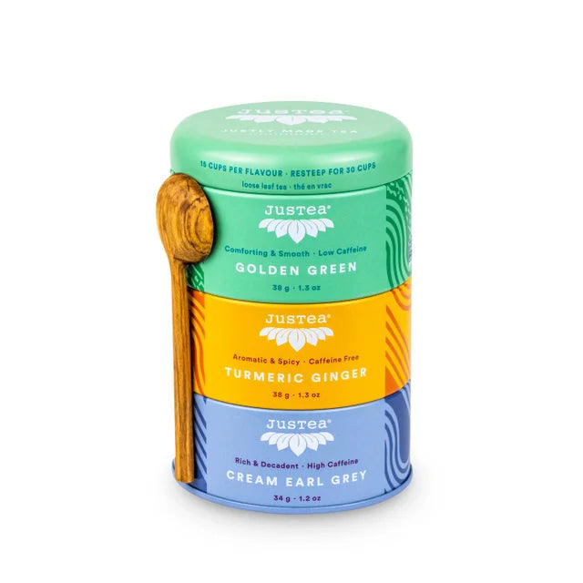 A photo of a tea trio from Justea. The tea comes in a 3 pack canister with a wooden spoon. This is the mixed pack with Golden Green Green Tea, Turmeric Ginger Herbal Tea, and Cream Earl Grey Black Tea. 