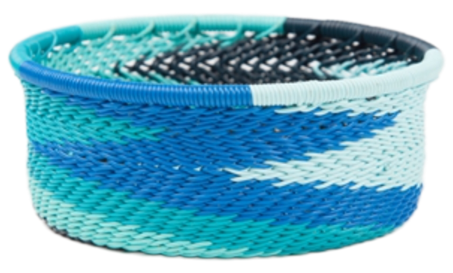 A photo of a small dish that is weaved like a basket made out of telephone wire with colors representing the african ocean with lots of tones of blue. 