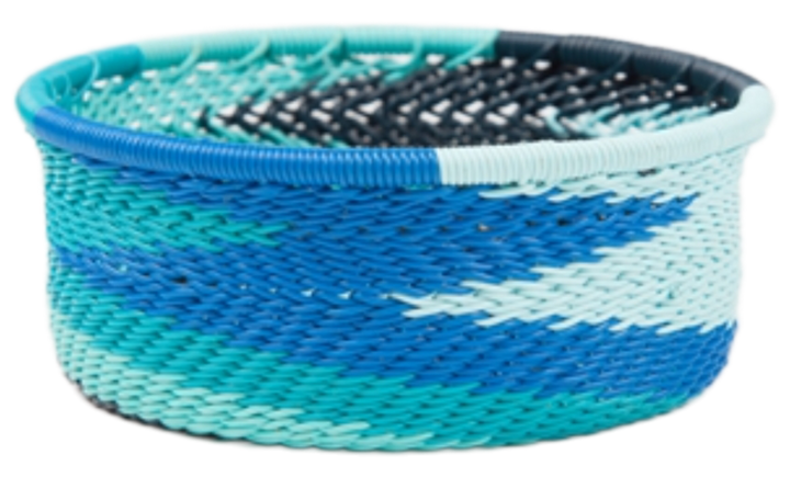 A photo of a small dish that is weaved like a basket made out of telephone wire with colors representing the african ocean with lots of tones of blue. 
