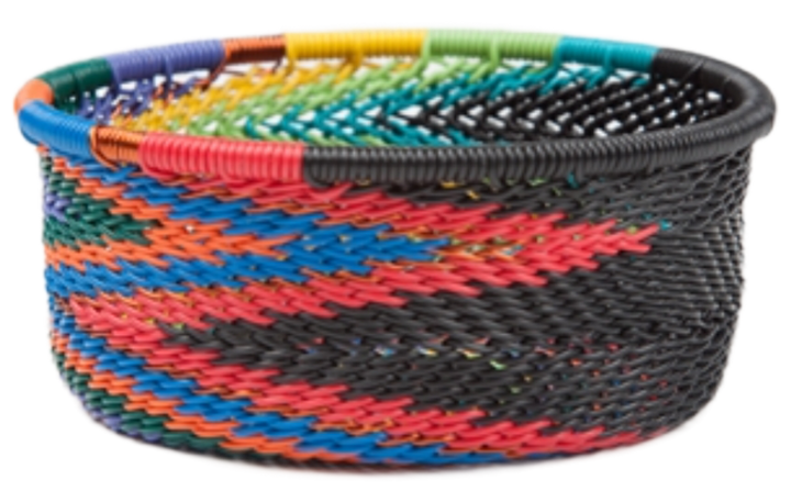 A photo of a small dish that is weaved like a basket made out of telephone wire with colors of the rainbow with bold black. 