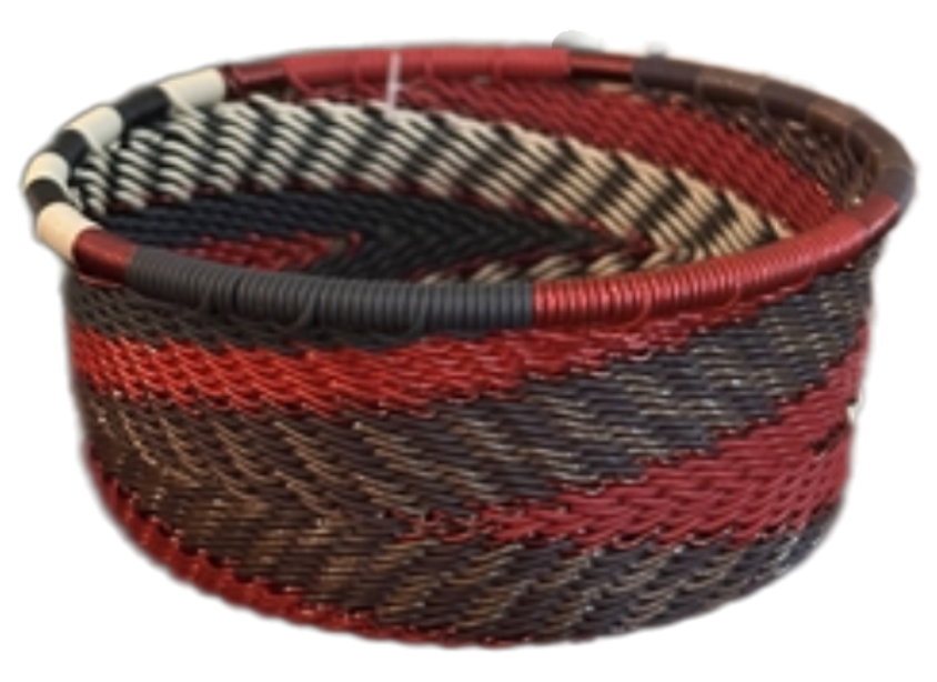 A photo of a small dish that is weaved like a basket made out of telephone wire with colors representing a red pepper color scheme, with reds, browns, black and whites. 
