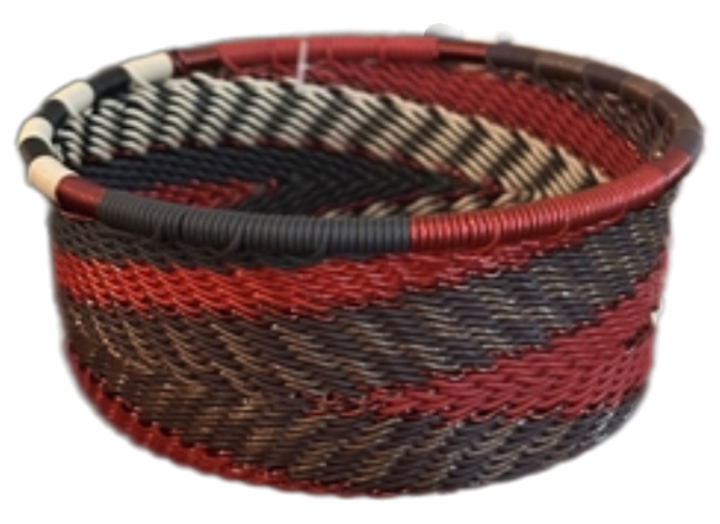 A photo of a small dish that is weaved like a basket made out of telephone wire with colors representing a red pepper color scheme, with reds, browns, black and whites. 