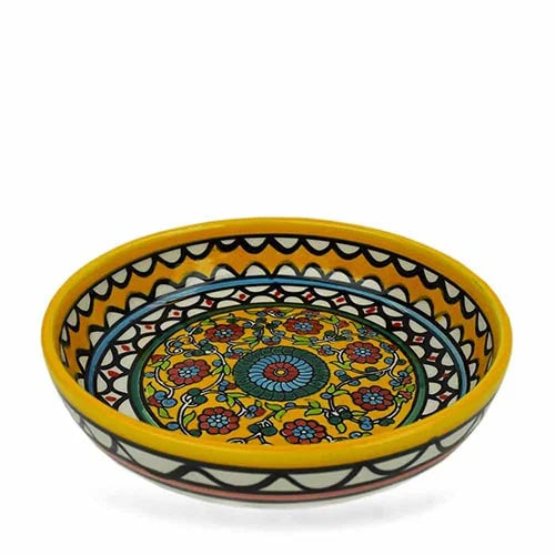 A photo of a large yellow bowl that is hand painted with flowers and colorful design from West Bank. The bowl itself is ceramic.